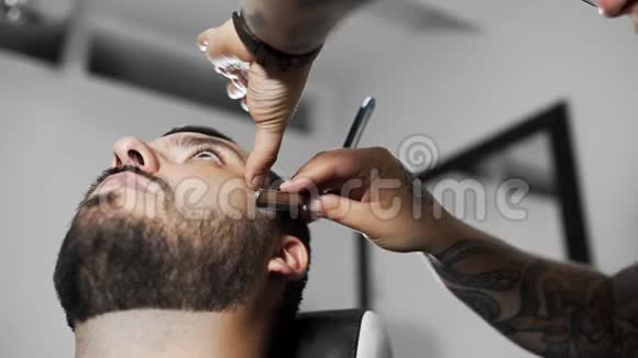 理发师用直剃须刀刮顾客在理发店理发和刮胡子视频的预览图