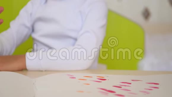 一个小孩子把手指放在油漆里用特写镜头把照片涂在一张纸上a的发展视频的预览图