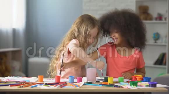 在幼儿园两个积极的多种族女孩用水彩作画爱好视频的预览图