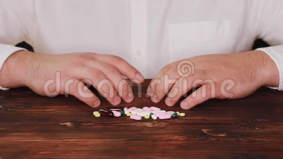 医生从一堆散落的药丸中取出一颗药丸瘾君子选择了一颗药丸桌子散落在桌子上视频的预览图
