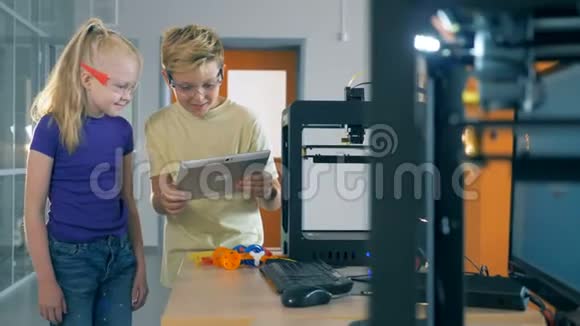 同学们在实验室里用3D打印机工作时看着平板电脑4K视频的预览图