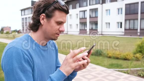 男人在手机上聊天和打字坐在长凳上视频的预览图