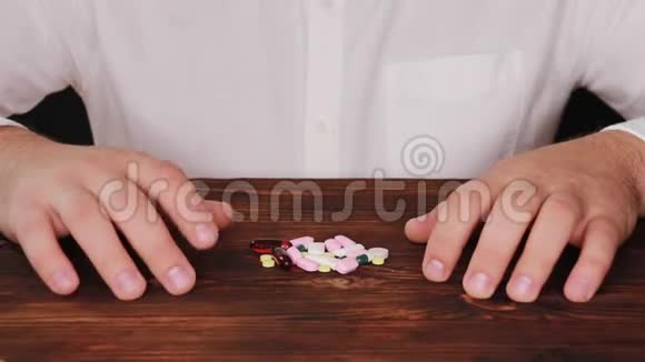 医生从一堆散落的药丸中取出一颗药丸瘾君子选择了一颗药丸桌子散落在桌子上视频的预览图
