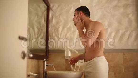 在热带岛屿的平房浴室里男人在镜子前刮胡子视频的预览图
