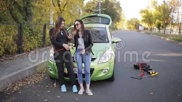 两个女人在路上的破车附近打手机路上的问题汽车的故障视频的预览图