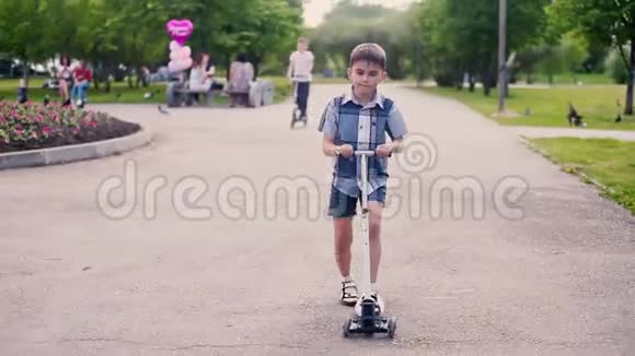 这个男孩在公园里的滑板车上滑冰夏天阳光明媚的天气里人们心情很好高清高清视频的预览图