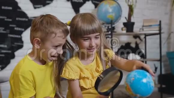 两个可爱的学生在教室里用放大镜有趣地学习地球仪的肖像在那儿视频的预览图