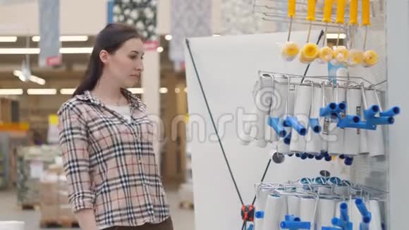 穿格子衬衫的女孩在商店里选择一个滚筒来油漆视频的预览图
