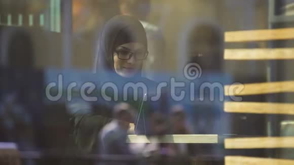 传统服装中的穆斯林女士坐在咖啡馆里聊天现代生活视频的预览图
