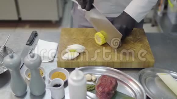一只戴着黑手套的专业未被识别的手正在厨房里把玉米切成圆形视频的预览图