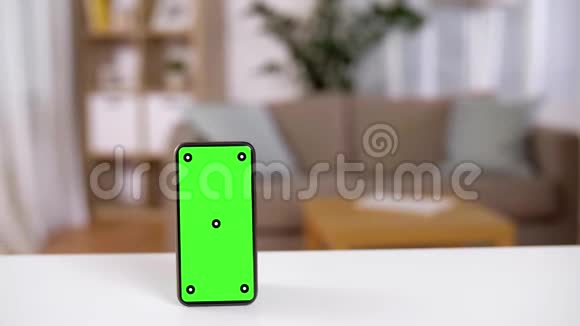 家庭桌上有绿色屏幕的智能手机视频的预览图