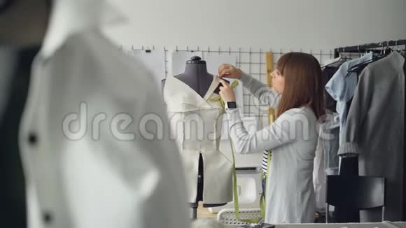 年轻漂亮的女人在新女人上班的时候用别针把衣服剪裁假人视频的预览图