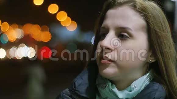 一位年轻女子站在风中的特写肖像夜城街道上悲伤孤独的女人春天视频的预览图