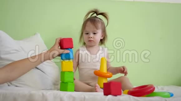 孩子们在床上玩立方体和妈妈一起建塔孩子和妈妈在床上玩彩色方块视频的预览图