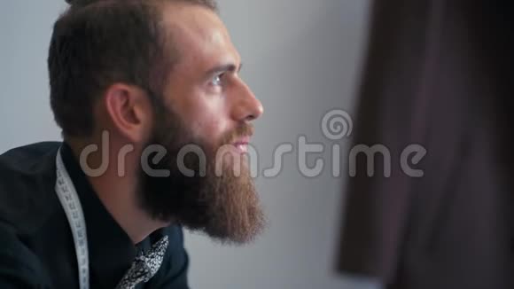 年轻的大胡子男裁缝带着卷尺笑着笑视频的预览图