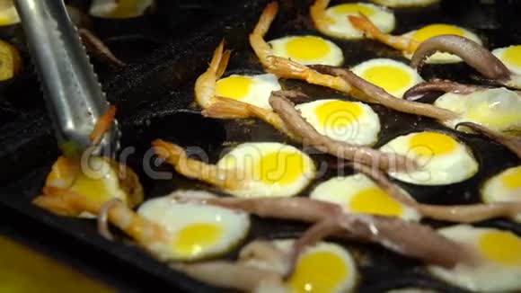 街头小贩用鱿鱼触角和对虾准备煎鹌鹑蛋视频的预览图
