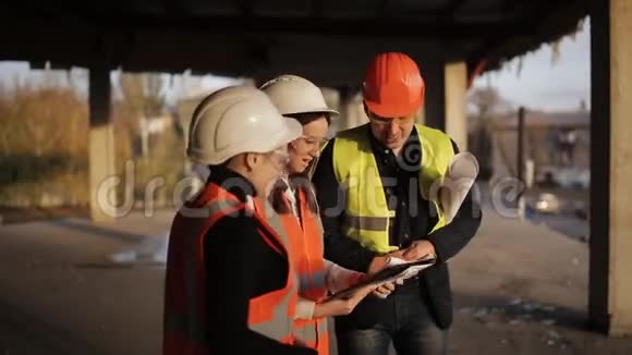 现场施工项目讨论建筑工人和两名妇女在现场讨论完成的工作计划视频的预览图