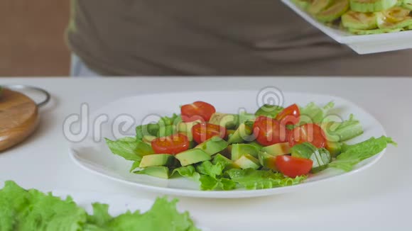 厨房里的一个男人正在准备一份牛油果西葫芦和樱桃番茄沙拉特写双手展开蔬菜视频的预览图