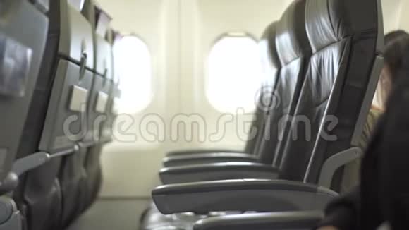 起飞前坐在飞机舱座位上的年轻女子坐在飞机舱里的女乘客靠近视频的预览图