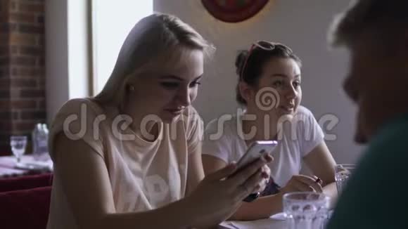 小女孩在咖啡馆的餐桌上用电话和朋友交流视频的预览图