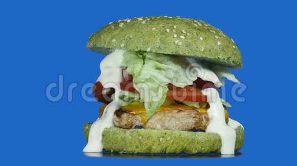 大的多汁的汉堡有绿色的面包洋葱西红柿黄瓜生菜和蛋黄酱围绕着它的轴线旋转视频的预览图