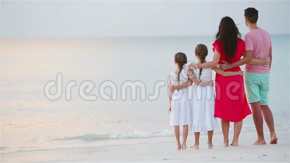海滩上幸福美丽的家庭日落时父母和孩子的后景视频的预览图