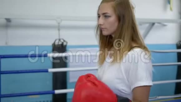 戴拳击手套的严肃女运动员在健身房打拳击前会感到温暖视频的预览图
