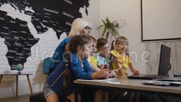 学校老师和一群小学生一起用笔记本电脑工作然后一起自拍教师视频的预览图