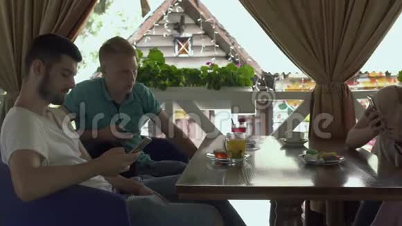 四个年轻人在咖啡馆里用手机视频的预览图