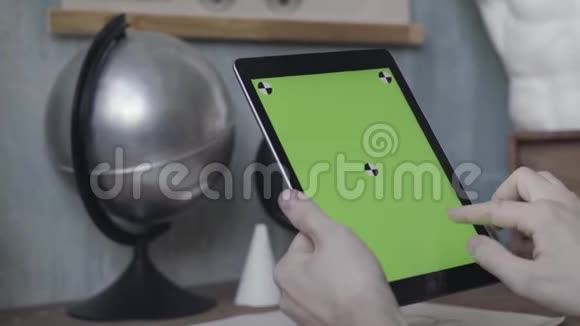 一个不知名的年轻人的手在笔记本电脑上轻敲和滚动银球旁边的木桌上有绿色的屏幕视频的预览图