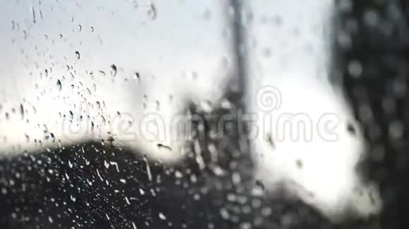 在恶劣天气时用模糊背景关闭车窗上的雨滴水滴落在玻璃上视频的预览图