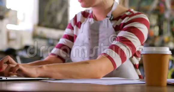 妇女在4k车间使用笔记本电脑时在便签纸上写字视频的预览图
