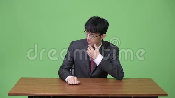 年轻的亚洲商人无聊地用手指敲桌子视频的预览图
