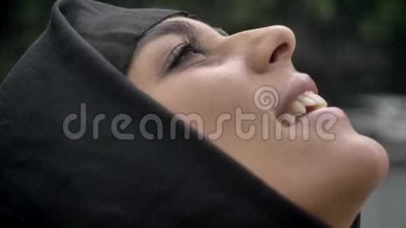 戴头巾的年轻穆斯林妇女站在雨中宗教观念天气观念侧视视频的预览图