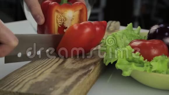 女人手在木切割板上切甜的红钟胡椒厨房桌子上切菜视频的预览图