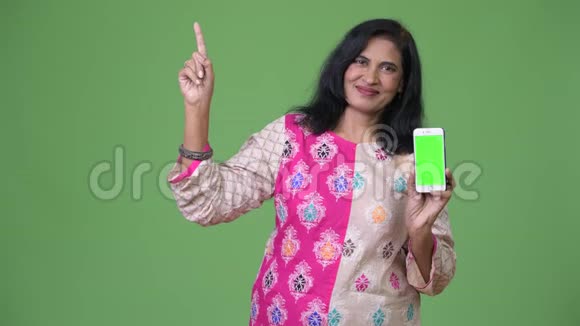 成熟快乐美丽的印度女人带着电话和手指视频的预览图