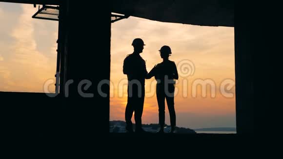 男人和女人在日落背景下的一栋大楼里工作关门视频的预览图