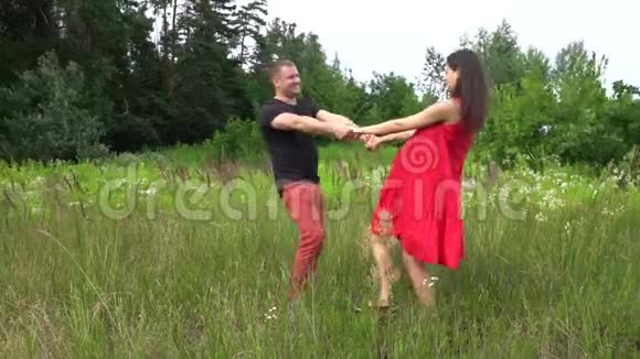 漂亮的夫妇男人和孕妇留着红色连衣裙的长发家庭视频的预览图