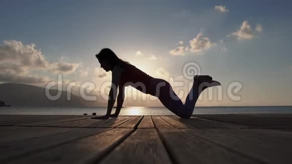 4K一个年轻女孩在日出时慢动作在海边做健身运动视频的预览图