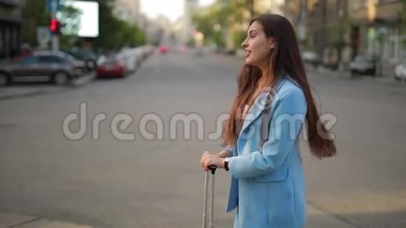 一个女人带着手提箱在城里等出租车视频的预览图