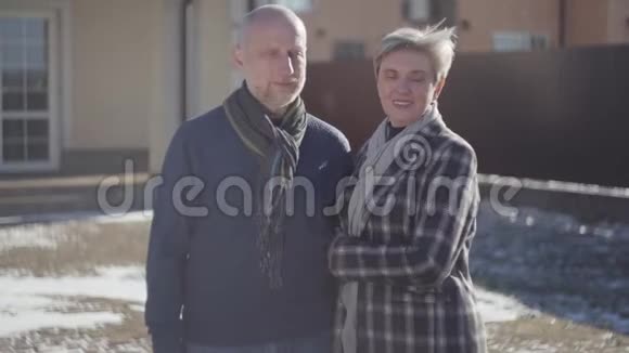 一对成年已婚夫妇站在凉爽的风和日丽的天气背景下的肖像家庭视频的预览图
