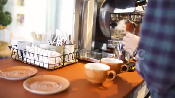一位身穿蓝色格子衬衫的咖啡师在咖啡屋里准备卡布奇诺或拿铁艺术把牛奶放进视频的预览图