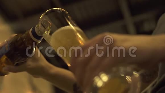 双手在酒吧餐厅或咖啡馆里用玻璃杯倒啤酒侍者双手倒瓶啤酒视频的预览图