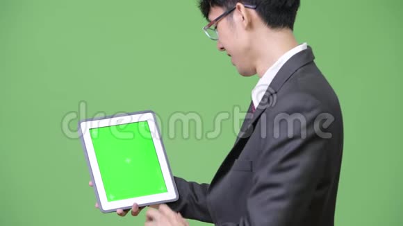 年轻快乐的亚洲商人将数码平板电脑展示给相机和触摸屏视频的预览图