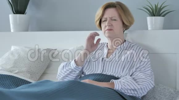 坐在床上头痛的老年妇女视频的预览图