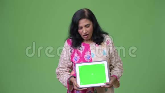 成熟快乐美丽的印度女人看着数字平板电脑时感到惊讶视频的预览图