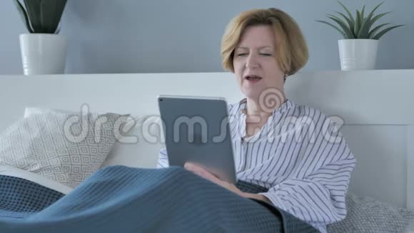 累高龄老人床上平板电脑在线视频聊天视频的预览图