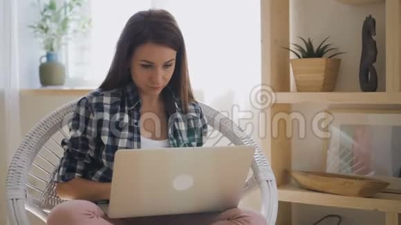 年轻的女设计师穿着格子衬衫在全新的笔记本电脑上工作视频的预览图