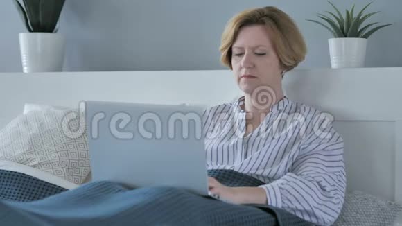 令人震惊的老年妇女在床上玩手机视频的预览图