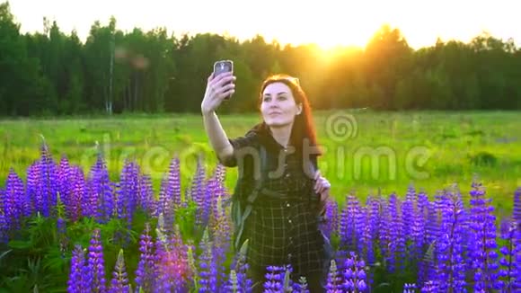日落时带着彩色背包的旅游女孩自拍视频的预览图
